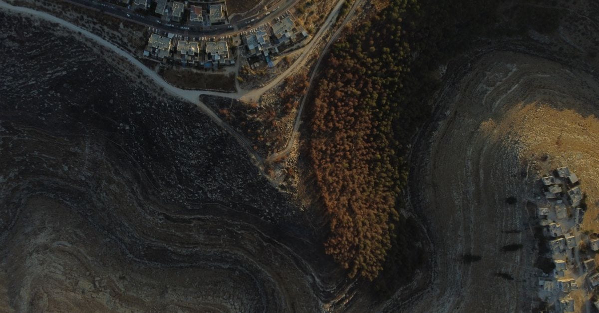 Photo: shay safrai / Pexels Stunning aerial view capturing residential and rugged natural landscape in Tekoa.