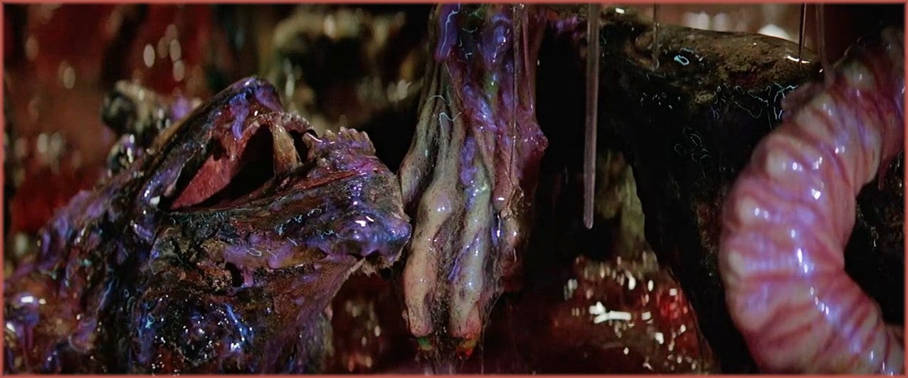 Film frame from The Thing (1982): extreme close-up of the Dog-Thing, showing the creature's internal matter in shades of purple, dark violet and deep burgundy, deliberately non-human colours chosen by Rob Bottin to avoid triggering a nausea response in the audience.