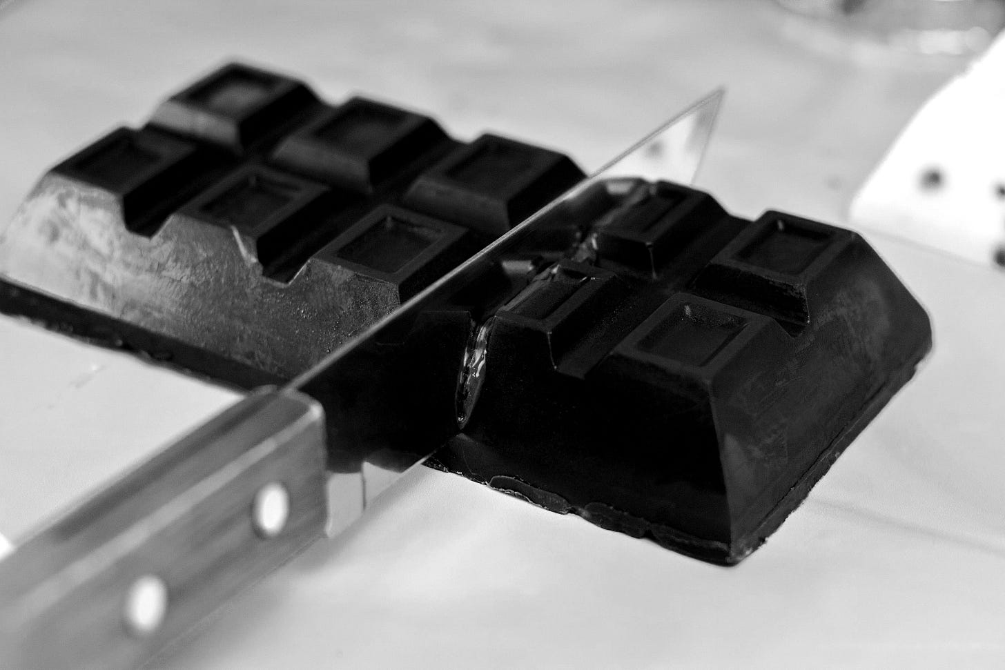 a knife cutting into a chocolate bar on a table a knife cutting into a chocolate bar on a table