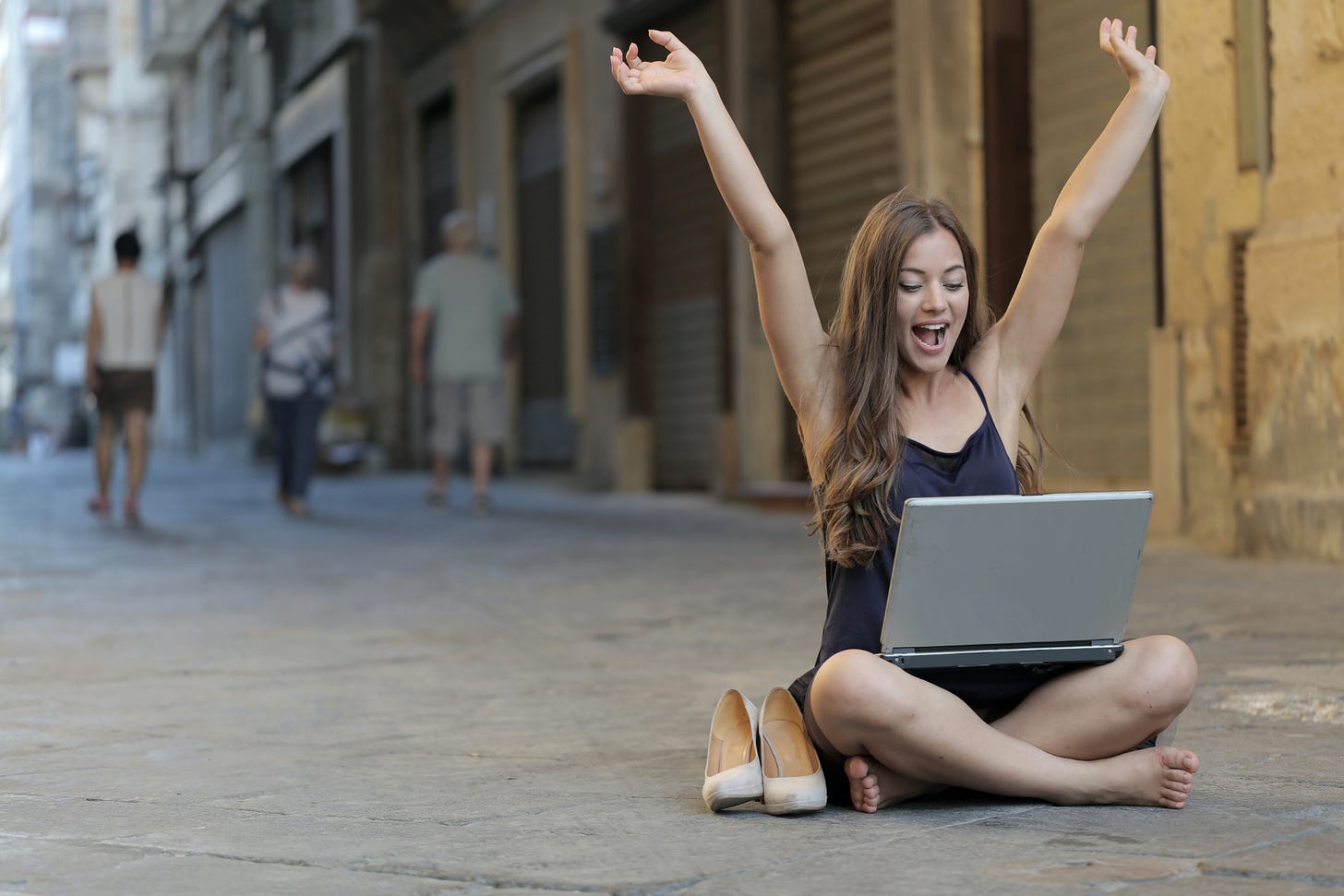 Woman Raising Her Hands Up While Sitting on Floor With Macbook Pro on Lap Woman Raising Her Hands Up While Sitting on Floor With Macbook Pro on Lap