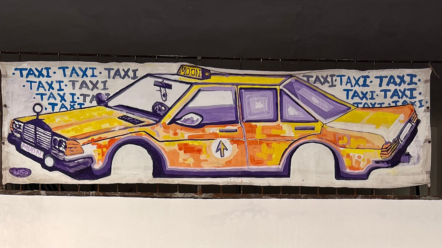 Painted artwork by Moroccan artist Barnoussi showing a stylized yellow taxi labeled “MOON,” surrounded by repeated handwritten “TAXI” text, blending urban transport imagery with a playful, surreal tone. Painted artwork by Moroccan artist Barnoussi showing a stylized yellow taxi labeled “MOON,” surrounded by repeated handwritten “TAXI” text, blending urban transport imagery with a playful, surreal tone.