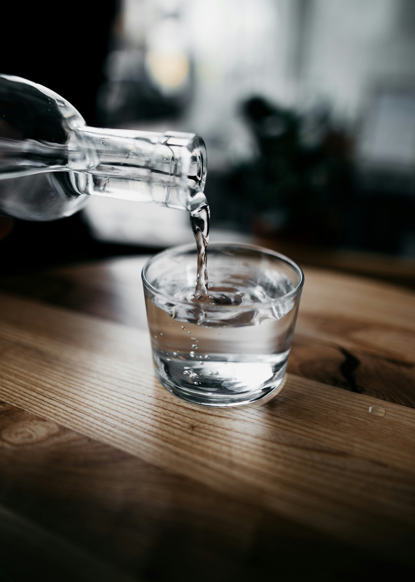 water being poured into a glass sitting on a table