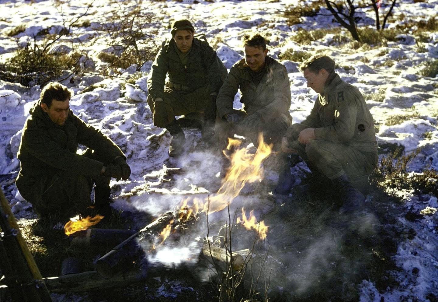 Exhausted GIs find a moment of respite, warming themselves by a fire in the snow-covered Ardennes during the brutal Battle of the Bulge, December 1944. Original color photograph by George Silk for LIFE Magazine.