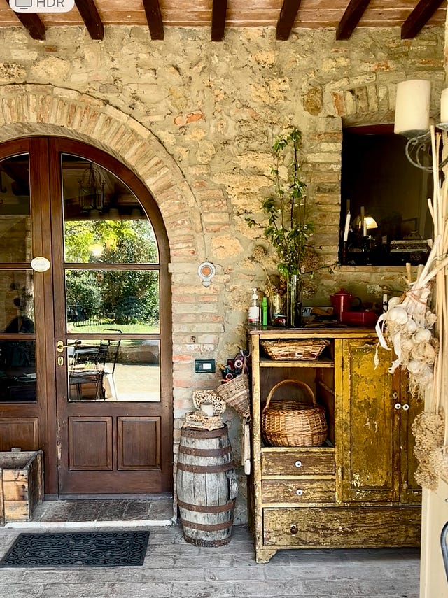 Rustic entrance at Poggio Etrusco with wooden door and vintage cabinet with baskets