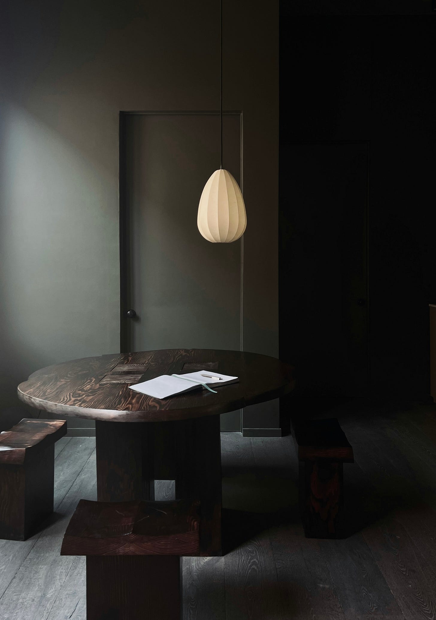 Dark wood dining table and benches showing expressive natural wood grain in a softly lit interior.