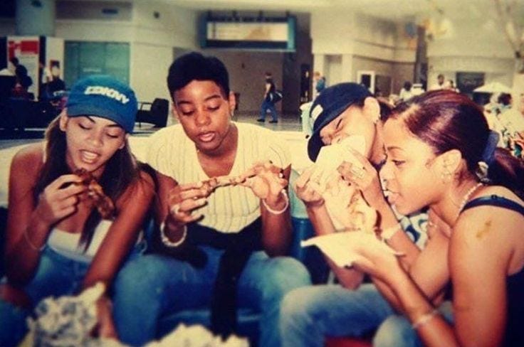 This may contain: four people sitting on the floor looking at something in their hands while one person looks at his cell phone