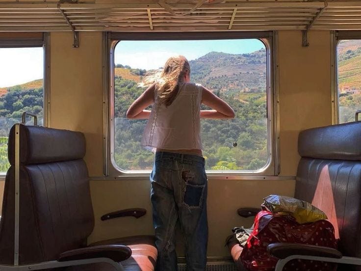 This may contain: a woman standing in front of a window on a train