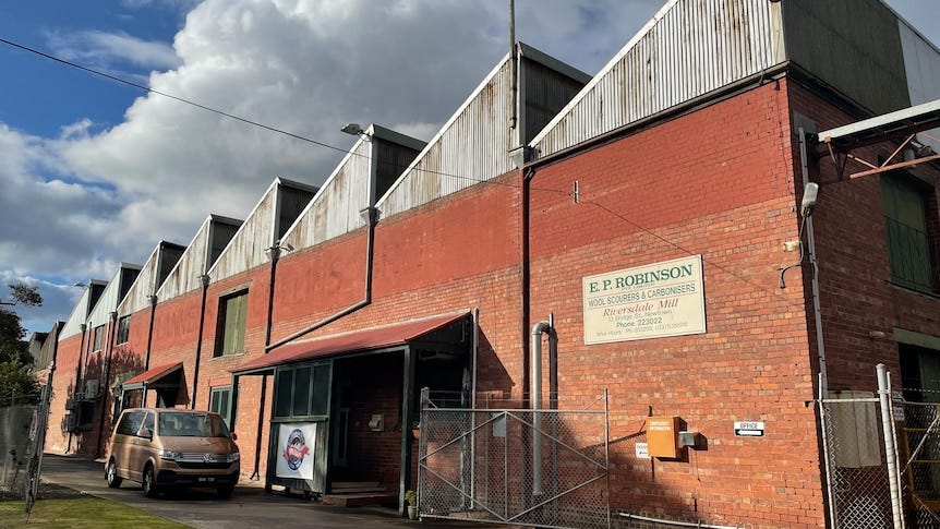 A brick wool factory with several angled iron roof gables