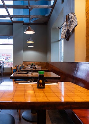 A photograph of a mostly empty restaurants with gray and yellow walls.