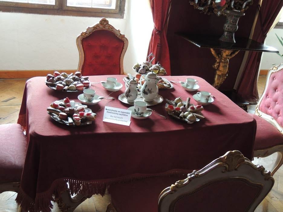 A table with a red tablecloth and plates of food

AI-generated content may be incorrect.