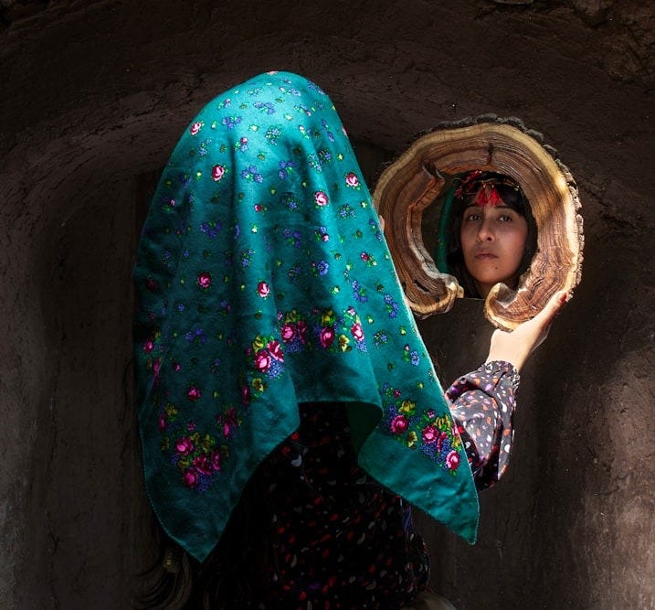 Woman in headscarf looks into ornate mirror Woman in headscarf looks into ornate mirror