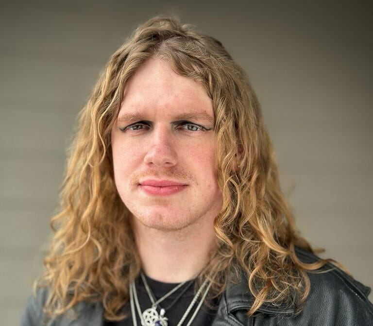 man with long blonde hair and leather jacket in posed photo