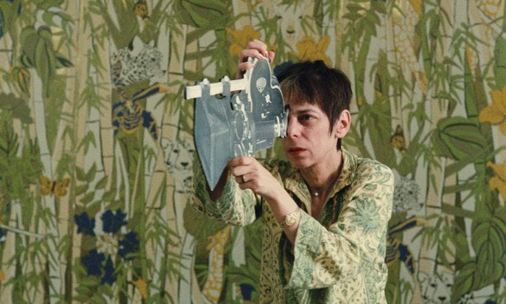 This may contain: a young man holding up a skateboard in front of a wallpapered background