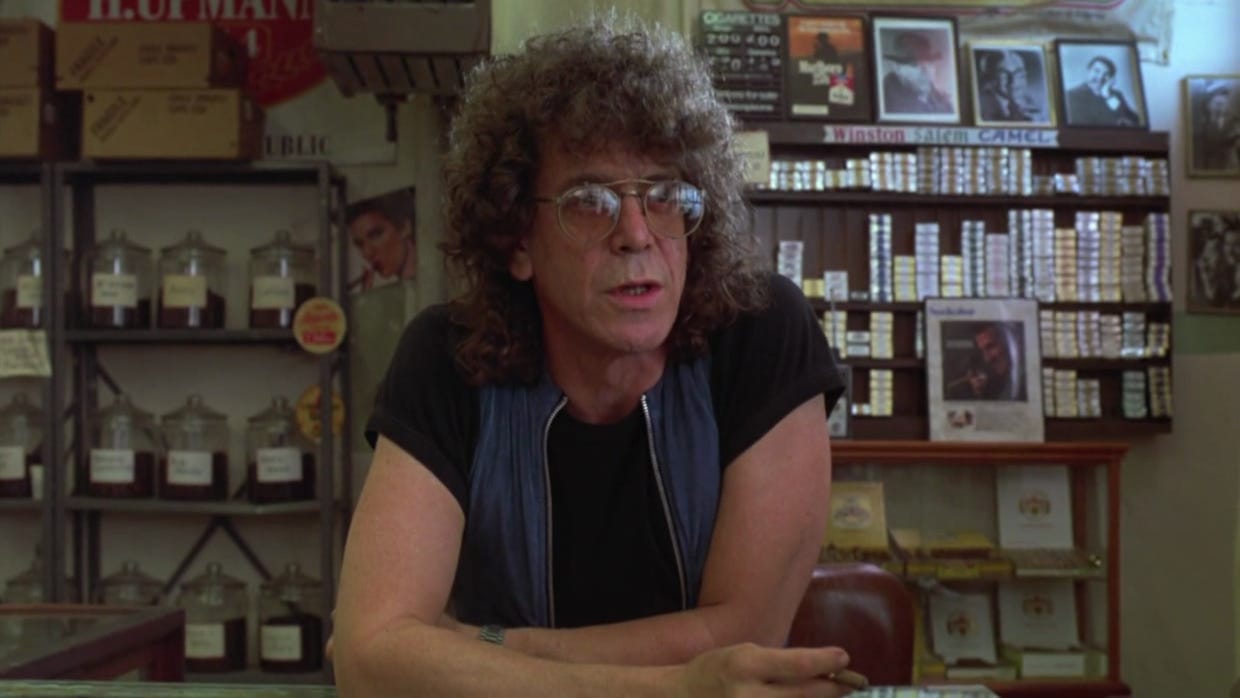 Photo of Lou Reed leaning against the counter in the tobacco store