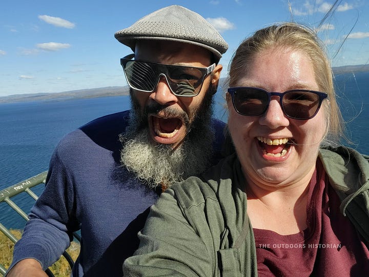 A split image. Left: A metal mesh walkway extending over a cliff edge. Right: A selfie of Emily and Eugene on the platform with a mix of wide-eyes and smiles while the lake expands behind them.