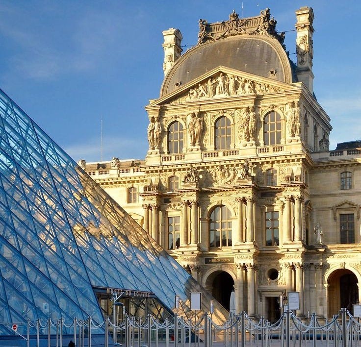 This may contain: a large building with a very tall glass pyramid in front of it's reflection