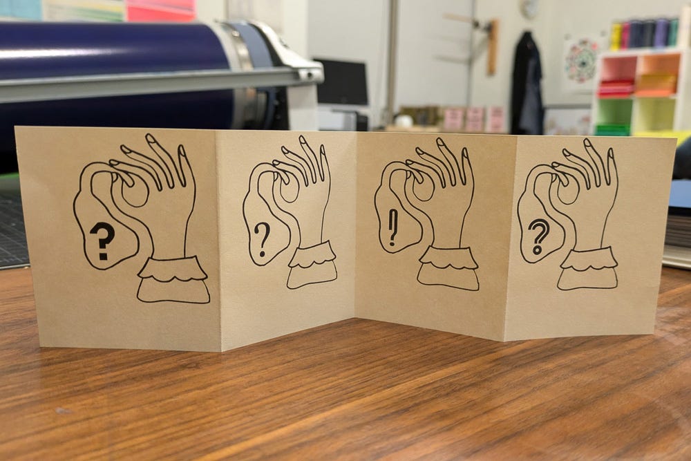 An accordion-fold book printed on cream-colored paper, featuring minimalist line art of a hand holding an ear. Each panel shows a subtle variation, with punctuation marks like question and exclamation points incorporated into the design, evoking themes of listening, sound, and communication.