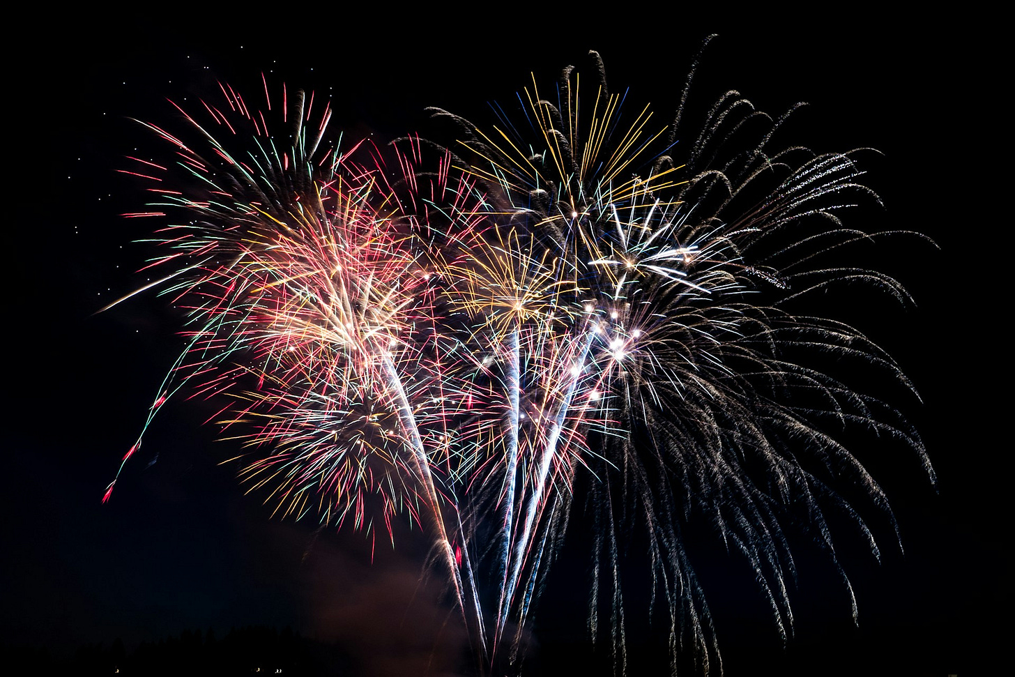 Pale coloured fireworks against a black sky.