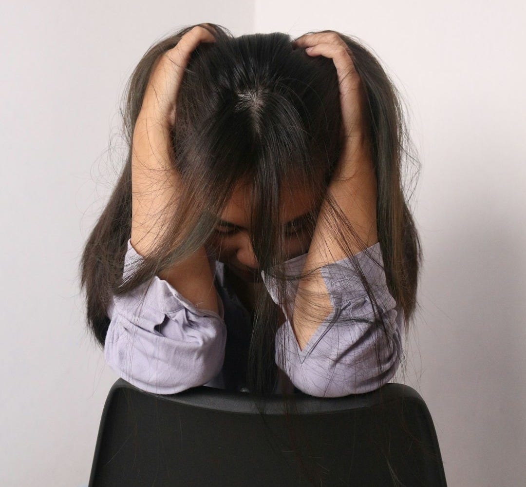 a woman sitting in a chair with her head in her hands