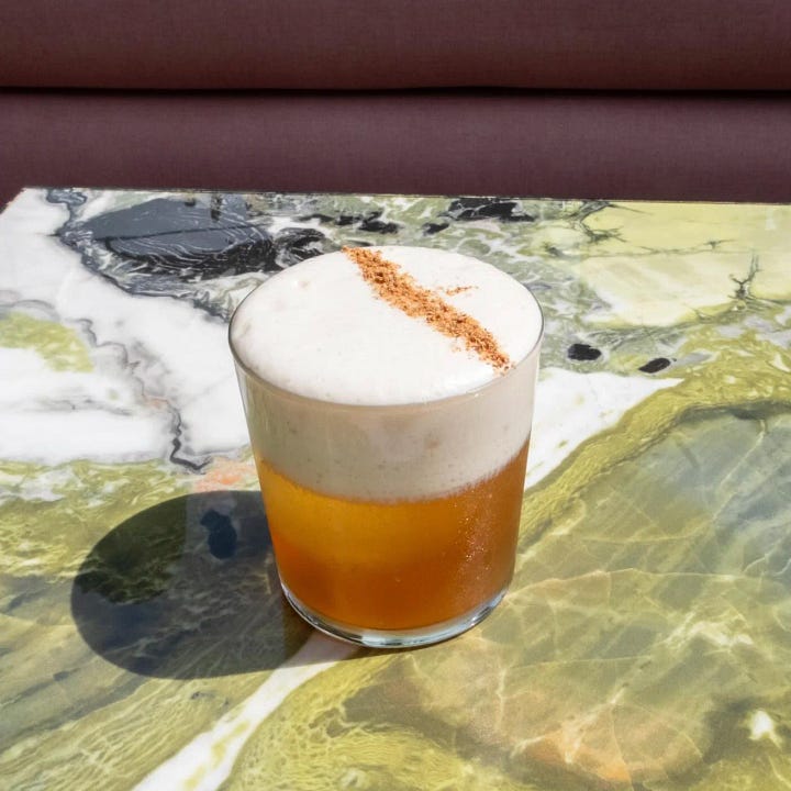 terraza bar en CDMX con sillones y barra para sentarse. Cocktail servido en un vaso sobre la mesa.