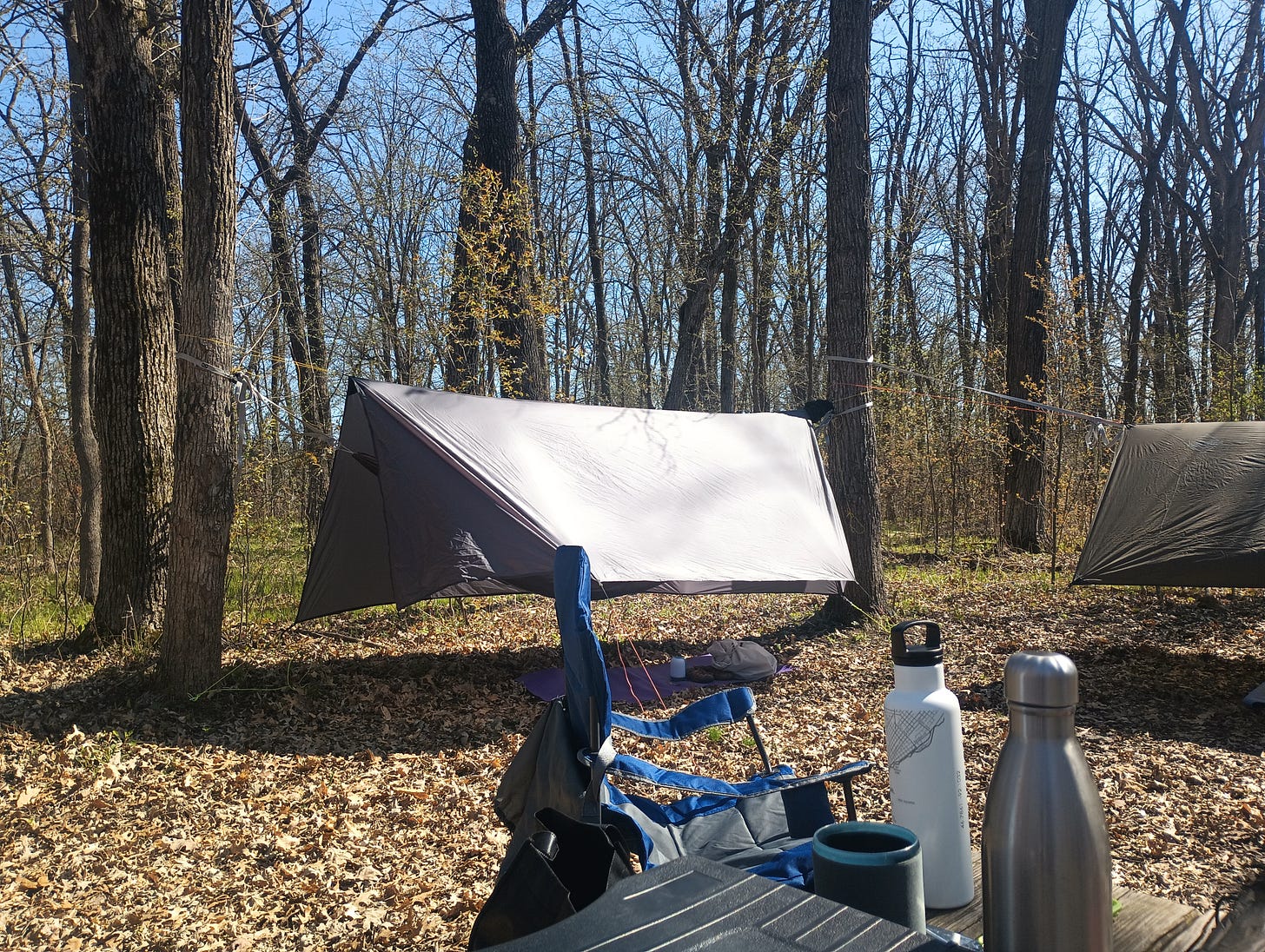 camping chair, table with water bottles, and two hammocks in the background