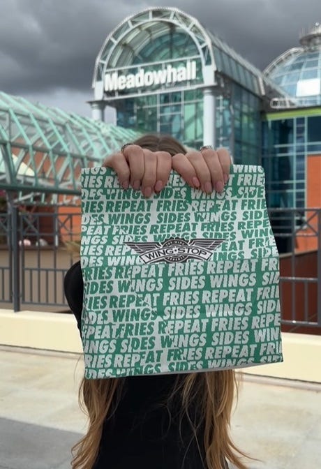A Wingstop bag held up in front of Meadowhall