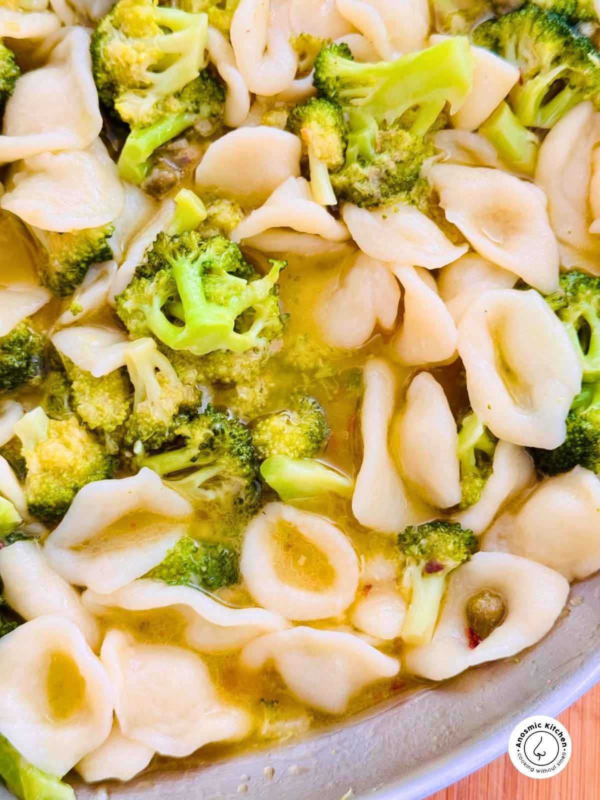 Bowl of orecchiette pasta with sautéed broccoli and lentils, served with olive oil and grated cheese.
