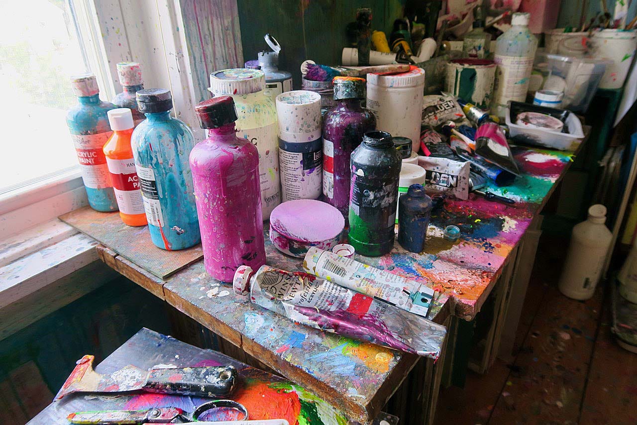A group of paint cans and brushes on a table

Description automatically generated