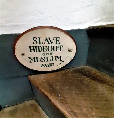 Outside of the stone Dobbin House restaurant; a welcome sign for the Springhouse Tavern and a closeup of candle-style lighting/ A sign for the Slave Hideout Museum, and a display of 3 slaves hiding in a crawl space. The owner of the restaurant stands in front of a huge stone fireplace in a room set up as a colonial kitchen.