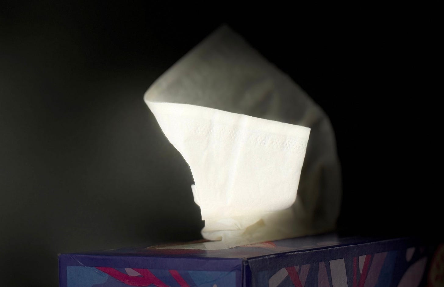 dramatic image of a tissue emerging from a box - against a black background