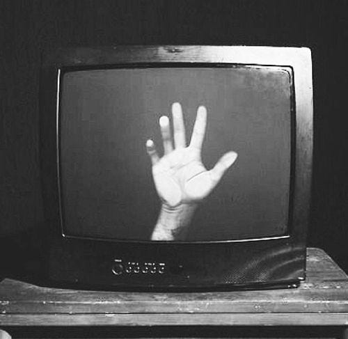 This may contain: black and white photograph of hand on television screen with two hands raised up in the air