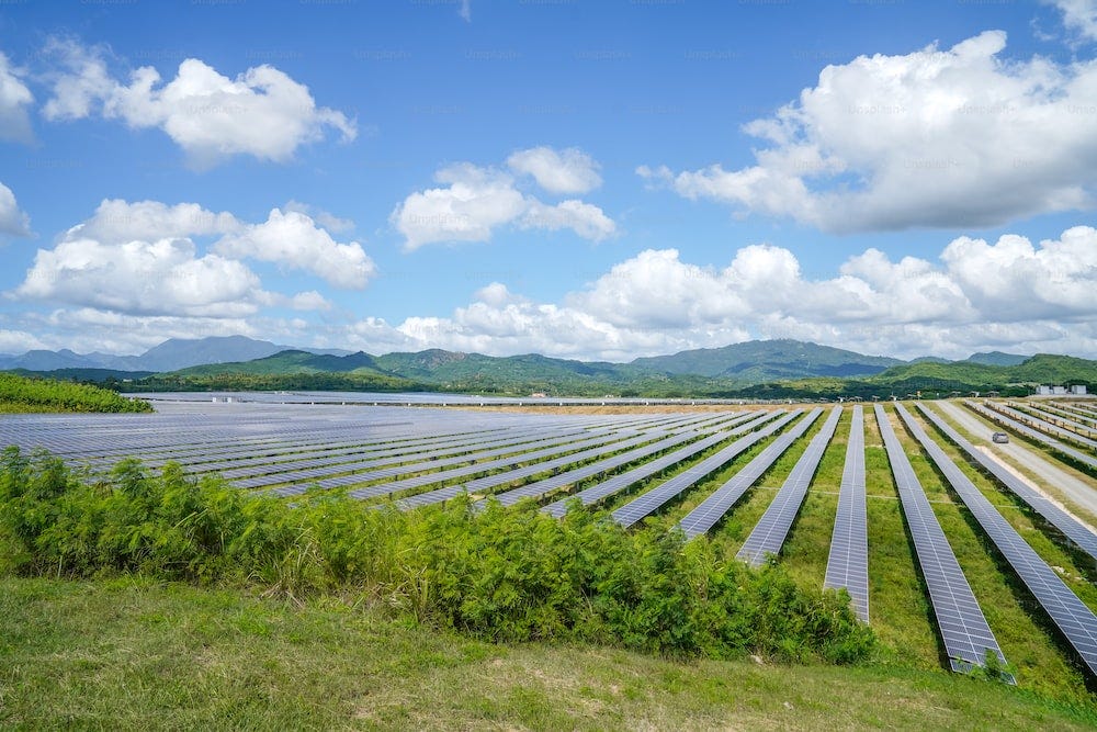 Filas de paneles solares en un campo con montañas al fondo