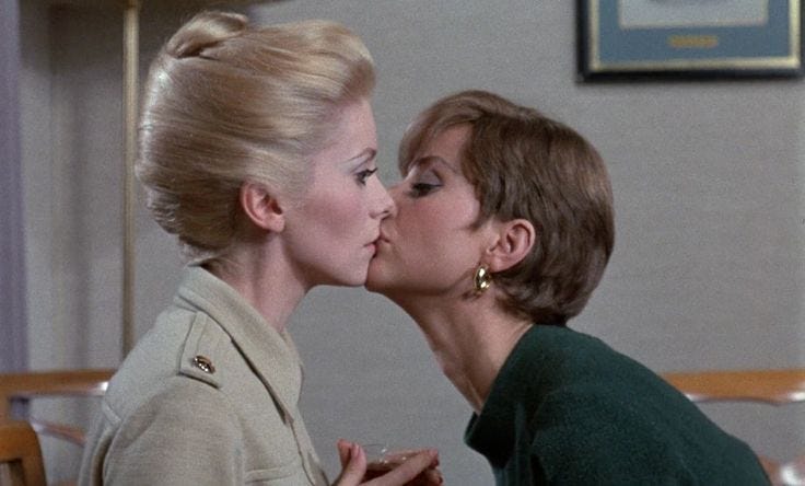 This may contain: two women kissing each other in front of a wall