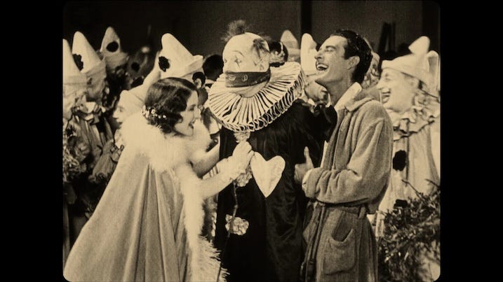 Chaney with couple: Lon Chaney’s clown character interacts with a man and woman laughing beside him in He Who Gets Slapped (1924).