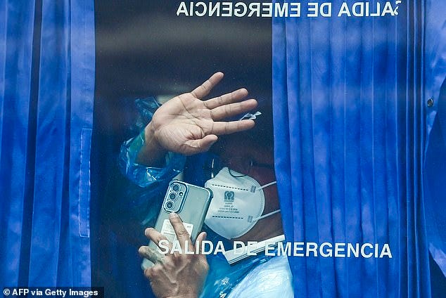 A passenger evacuated from the Dutch flagged hantavirus-stricken cruise ship MV Hondius waves aboard a military bus after being transferred by boat to the industrial port of Granadilla de Abona on the island of Tenerife in Spain's Canary Islands on May 10