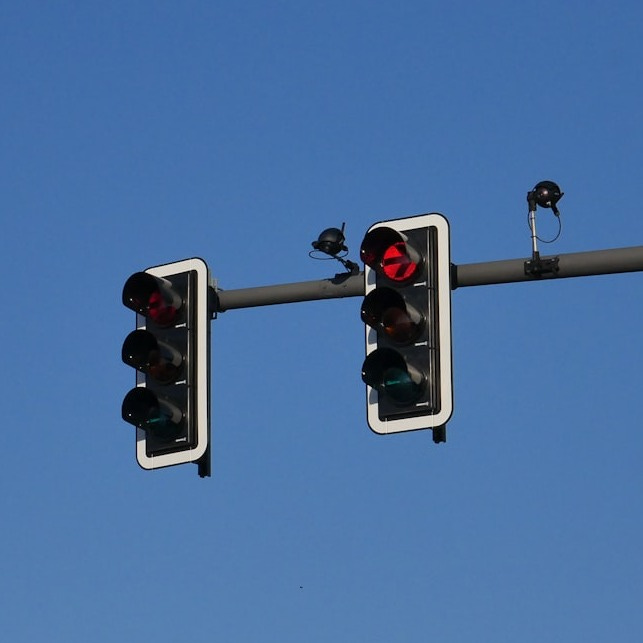 a couple of traffic lights hanging from a metal pole a couple of traffic lights hanging from a metal pole