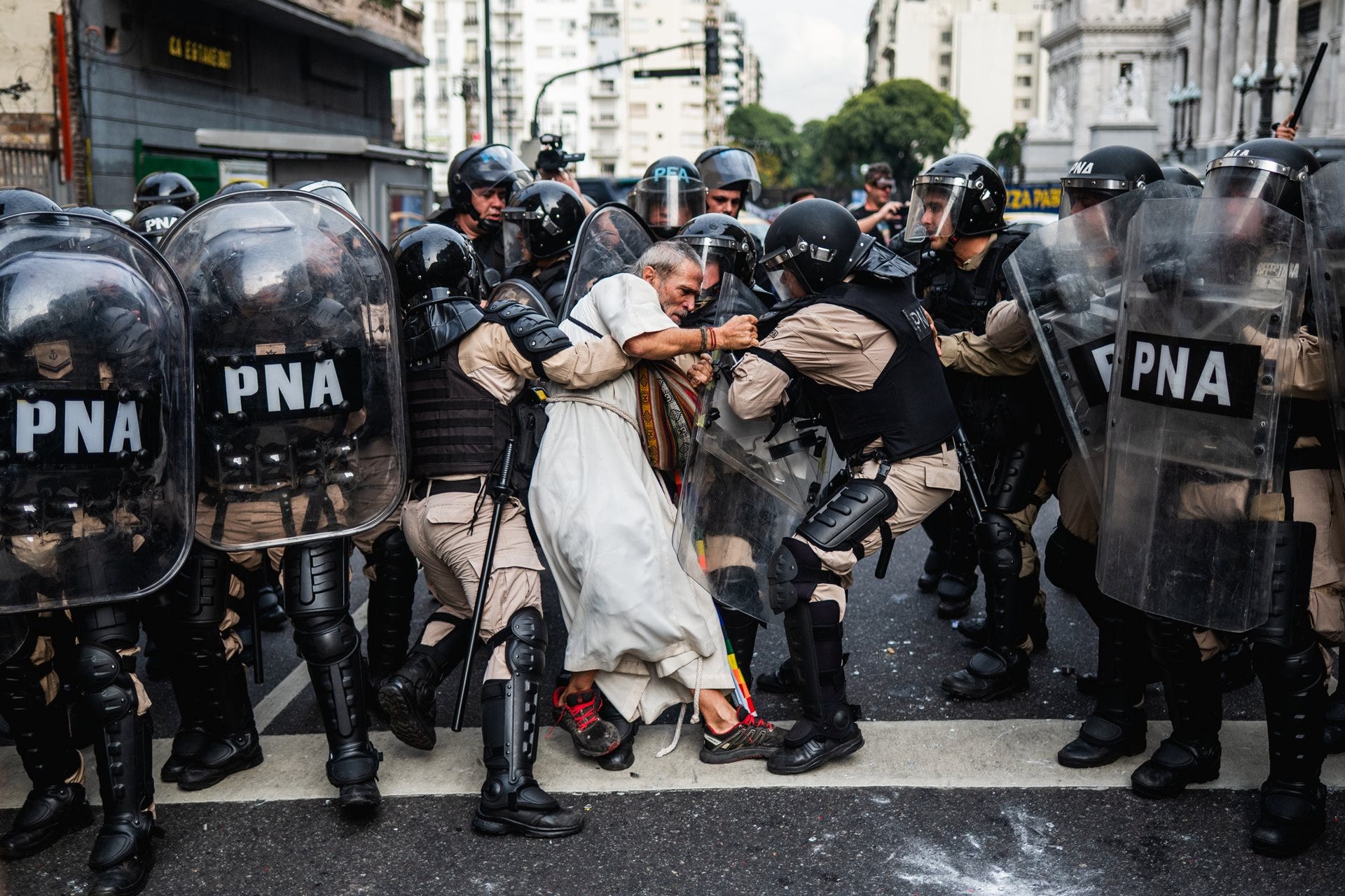 Police detain Father Jorge “Chueco” Romero during a pensioners’ protest in Buenos Aires, Argentina. Members of the “Opción por los Pobres” (Option for the Poor) clergy have joined weekly demonstrations against pension freezes and cuts to essential medical coverage, 14 May 2025. © Tadeo Bourbon Police detain Father Jorge “Chueco” Romero during a pensioners’ protest in Buenos Aires, Argentina. Members of the “Opción por los Pobres” (Option for the Poor) clergy have joined weekly demonstrations against pension freezes and cuts to essential medical coverage, 14 May 2025. © Tadeo Bourbon