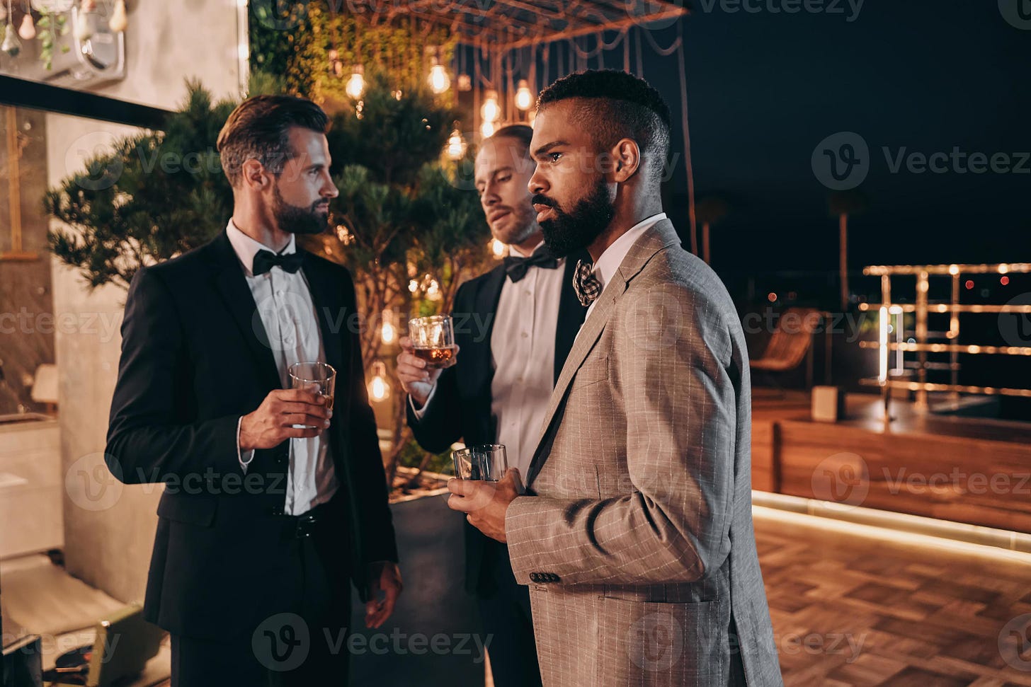 Three handsome men in suits drinking whiskey and communicating while ... Three handsome men in suits drinking whiskey and communicating while ...