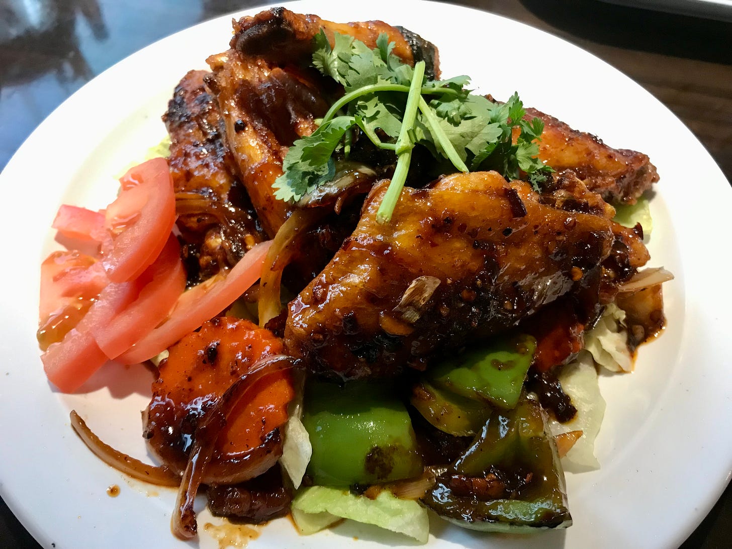 spicy Buffalo ginger wings served atop peppers, onions, carrot, and tomato