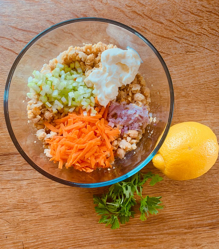 Mashed chickpeas in a bowl with salad ingredients.