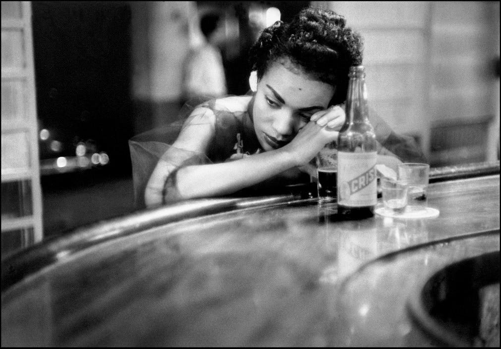 A girl in a bar with a beer, deep in thought
