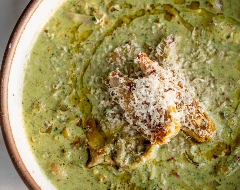 Top down of a bowl of white bean soup topped with seared artichoke hearts and vegan parm.