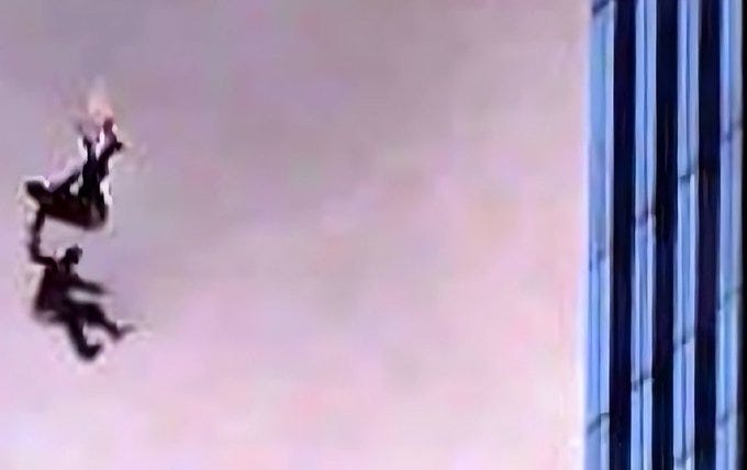 Two silhouetted figures falling, holding hands, against a backdrop of a tall building with vertical blue and white stripes. Smoke and debris are visible in the sky.