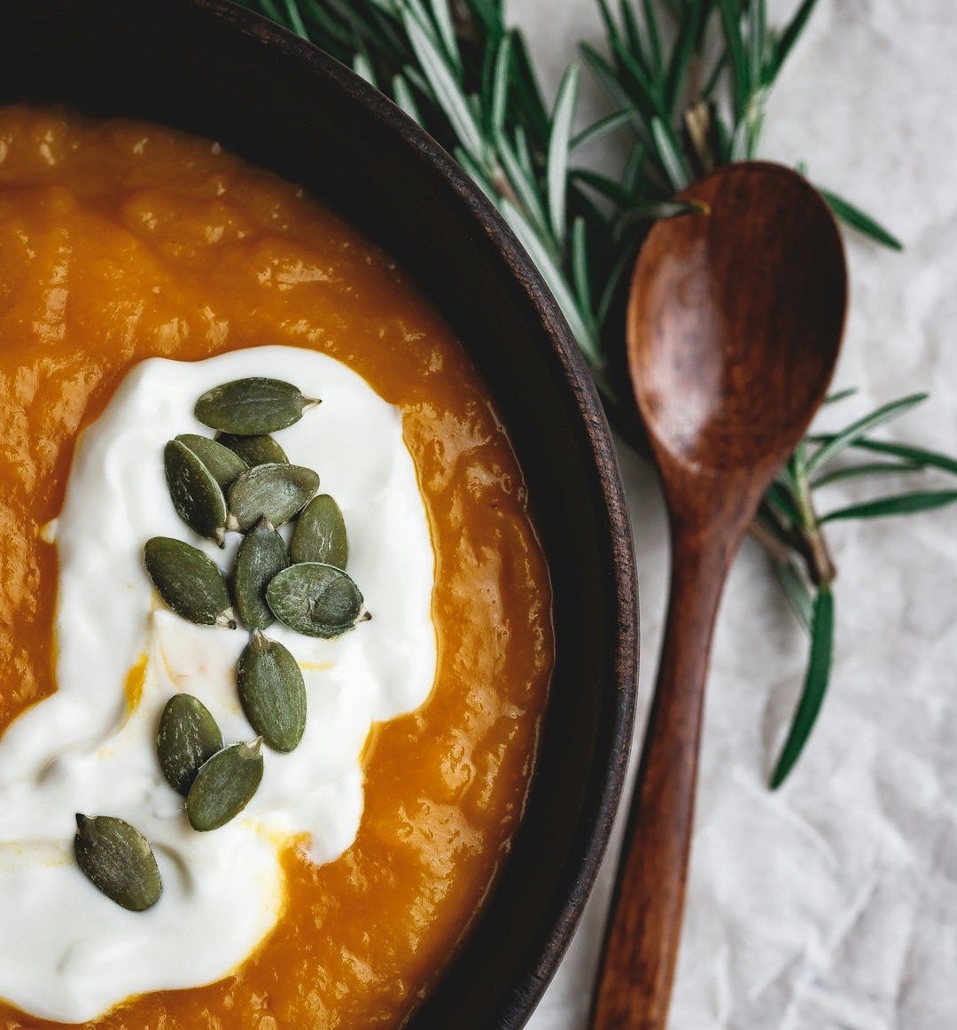 stew in round wooden bowl beside wooden spoon