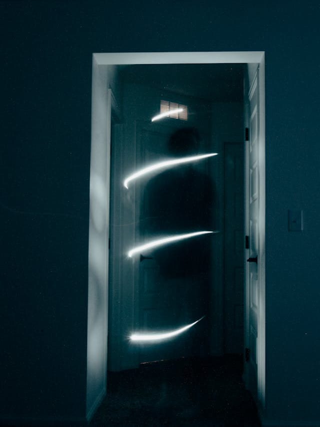 Dans un couloir sombre se tient une silhouette encerclée par des anneaux de lumière étrange