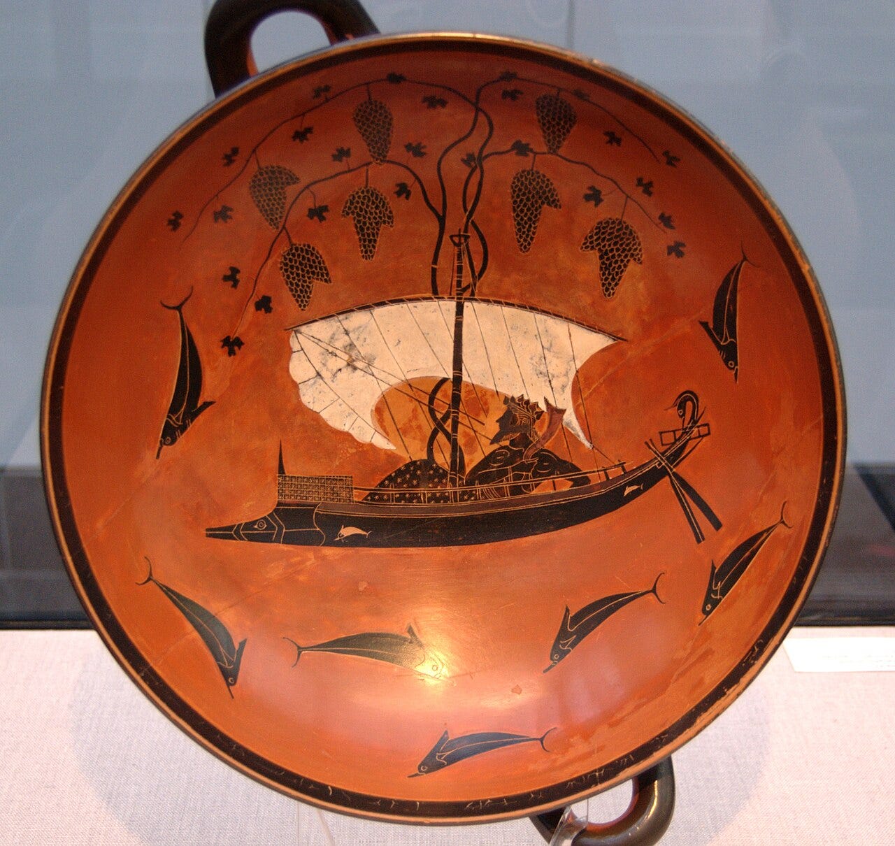 The Dionysus Cup by Exekias: Dionysus reclining in a ship with a grapevine growing from the mast, dolphins around it