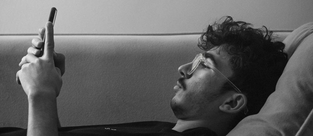 a man laying on a couch holding a cell phone