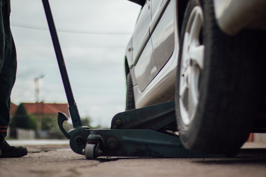 Tire technician lifting a car with a car jack