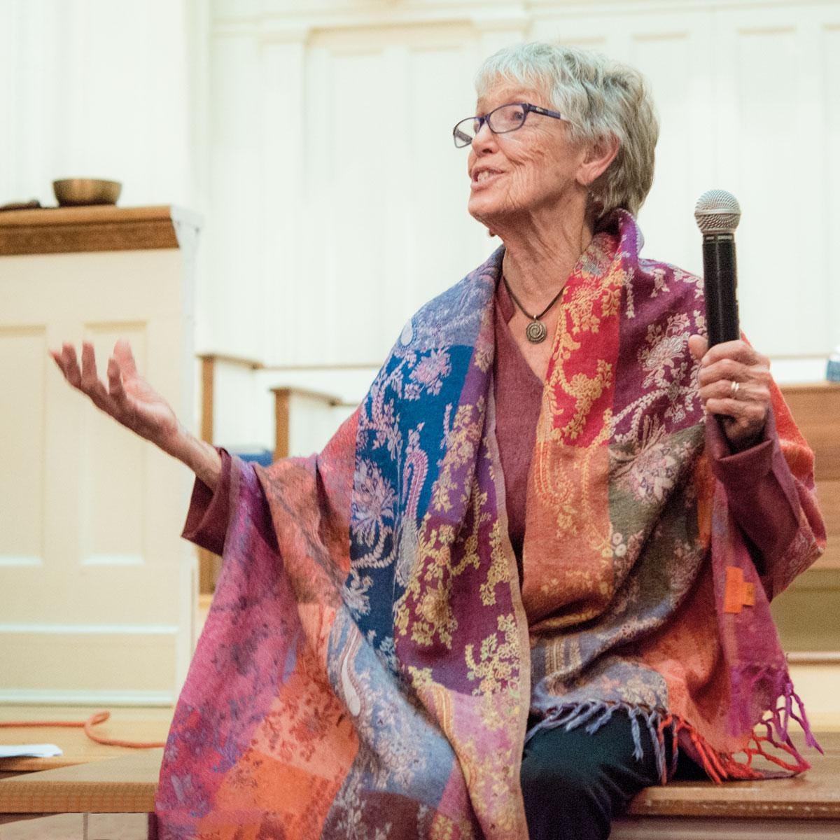 A person sitting on a bench holding a microphone

Description automatically generated