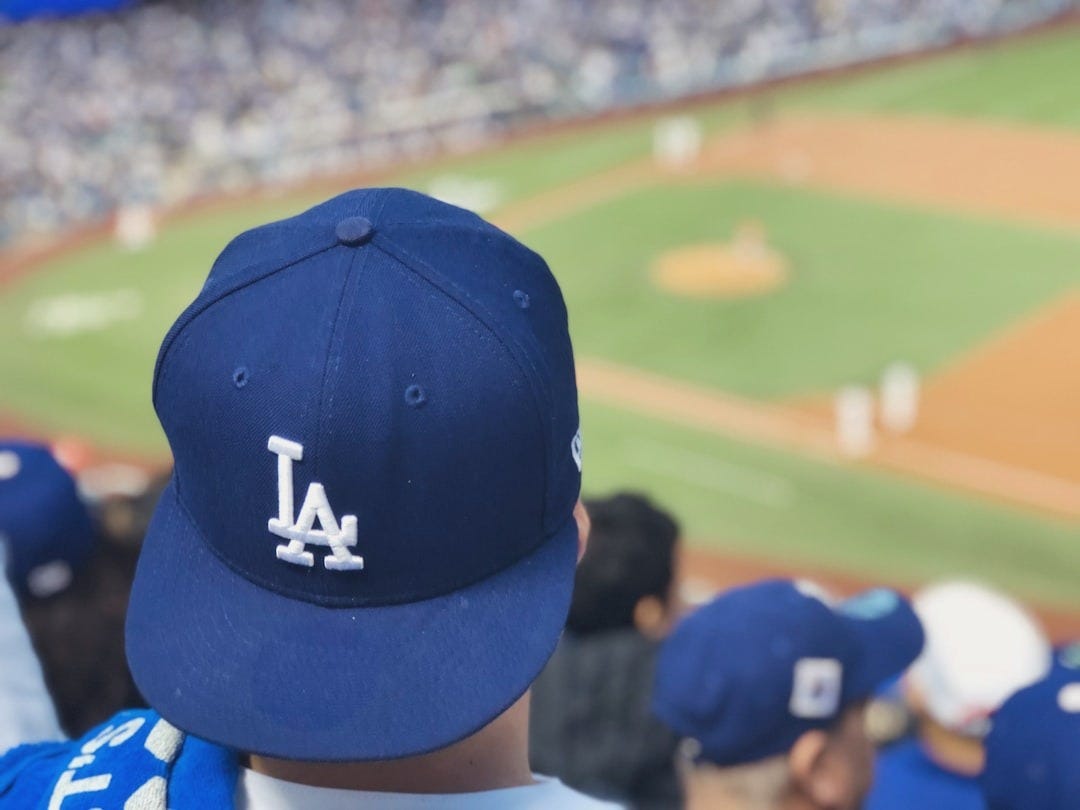 selective focus photography of person wearing LA Dodgers cap looking at field selective focus photography of person wearing LA Dodgers cap looking at field